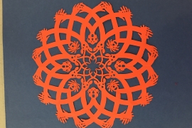 an intricate orange paper craft decoration created by Allan Troxler ’69 